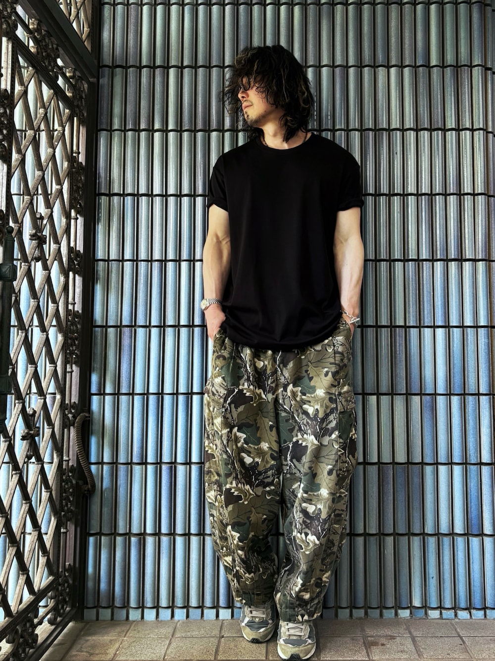 グリーン系のカーゴパンツ、グレー系のスニーカー、ブラック系のTシャツ/カットソーを着用したメンズの春コーディネートの1枚目の写真