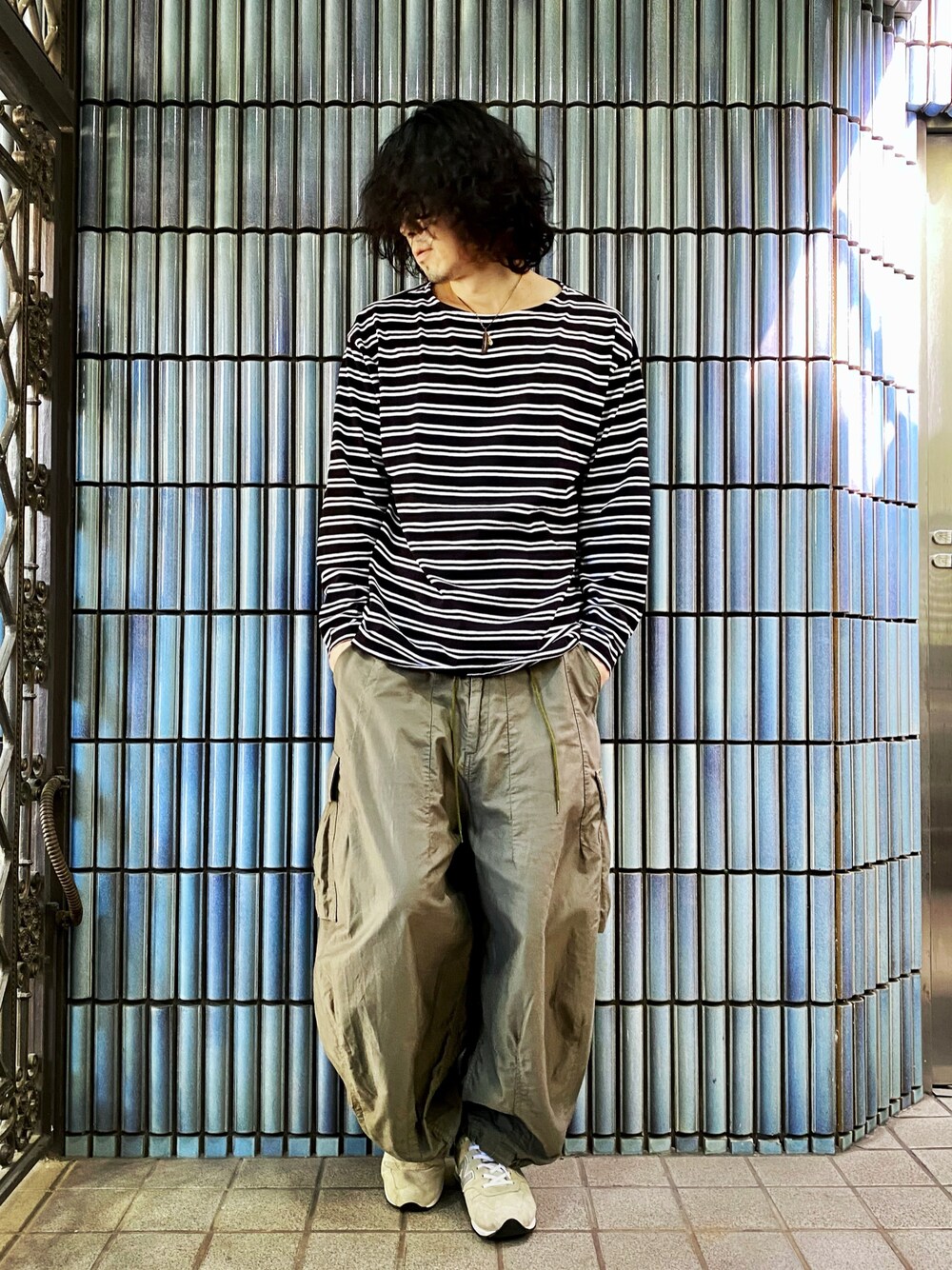 ブラック系のTシャツ/カットソー、グリーン系のカーゴパンツ、グレー系のスニーカーを着用したメンズの秋コーディネートの1枚目の写真