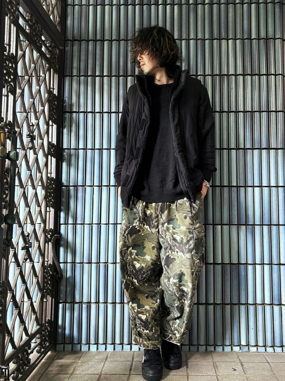 ブラック系のダウンベスト、グリーン系のカーゴパンツ、ブラック系のスニーカーを着用したメンズの冬コーディネートの1枚目の写真