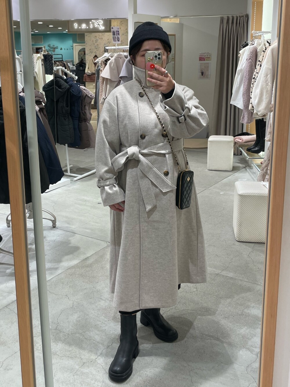 ベージュ系のその他アウター、ブラック系のブーツ、ブラック系のニットキャップ/ビーニーを着用したレディースの秋コーディネートの1枚目の写真