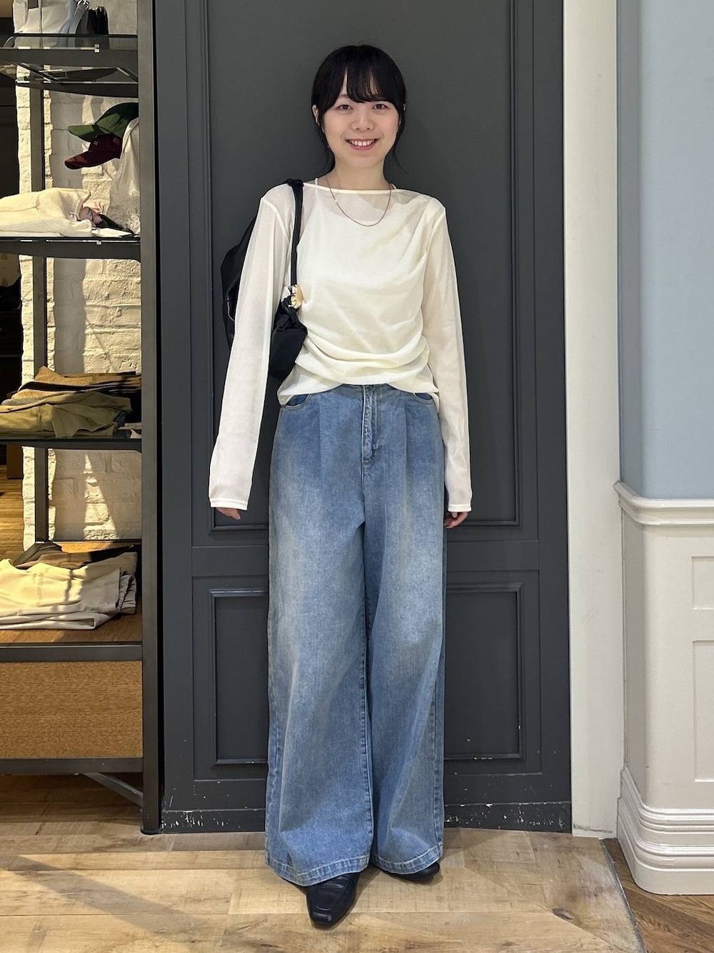 ブラック系のショルダーバッグ、ブルー系のデニムパンツ、ホワイト系のTシャツ/カットソーを着用したレディースの秋コーディネートの1枚目の写真