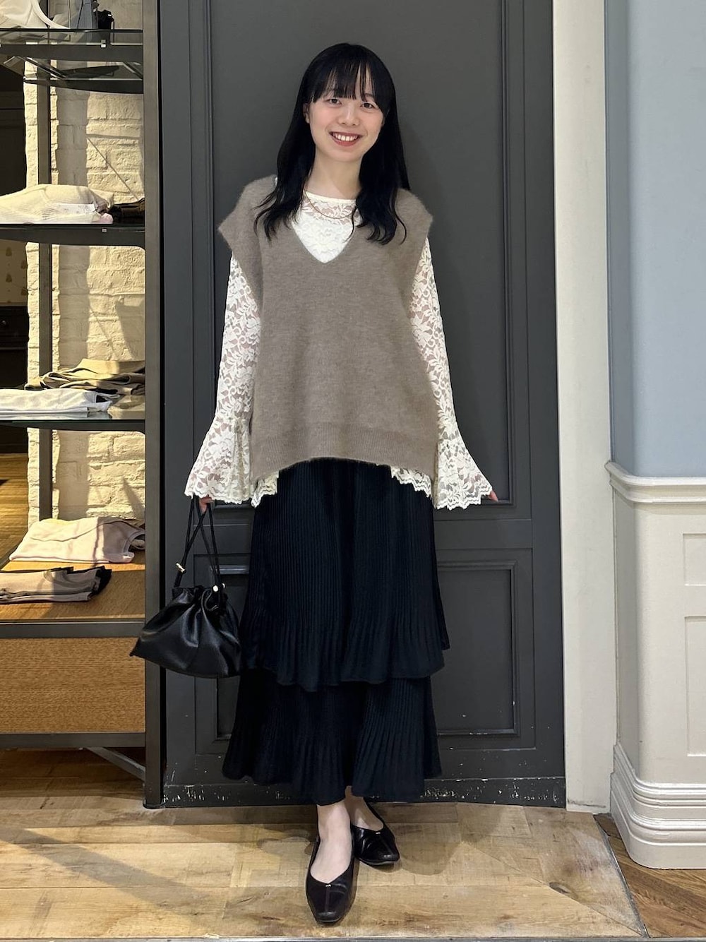 ブラック系のショルダーバッグ、ベージュ系のTシャツ/カットソー、ブラック系のスカートを着用したレディースの秋コーディネートの1枚目の写真