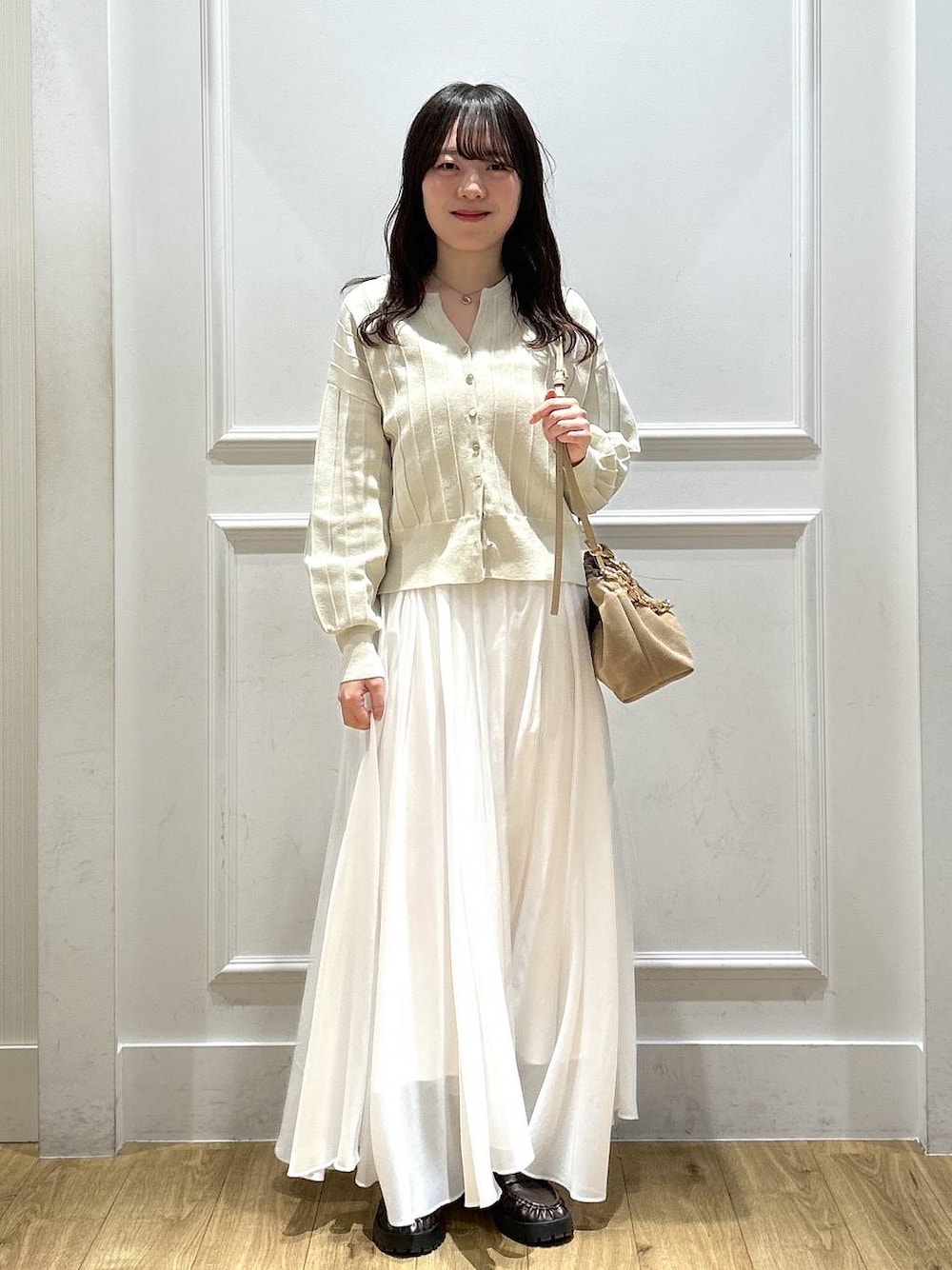 ベージュ系のカーディガン/ボレロ、ホワイト系のスカート、ブラウン系のローファーを着用したレディースの春コーディネートの1枚目の写真