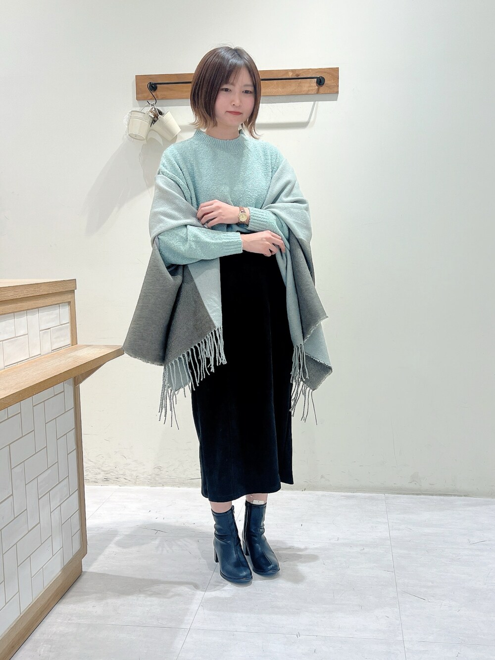 ブラック系のスカート、グリーン系のニット/セーター、ベージュ系のドレスシューズを着用したレディースの秋コーディネートの1枚目の写真