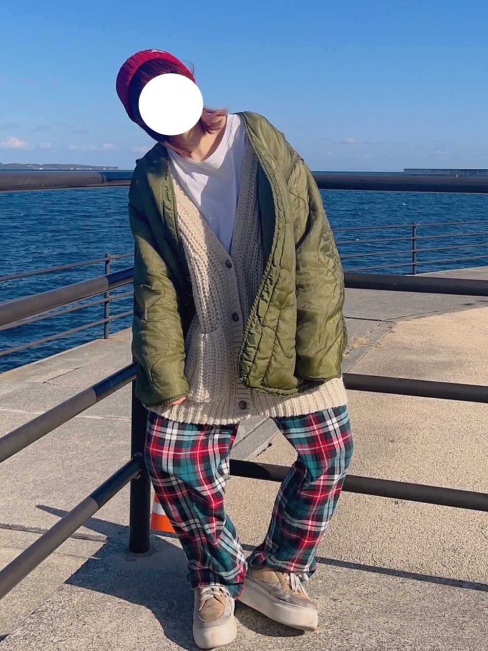 ベージュ系のカーディガン/ボレロ、レッド系のパンツを着用したレディースの冬コーディネートの1枚目の写真