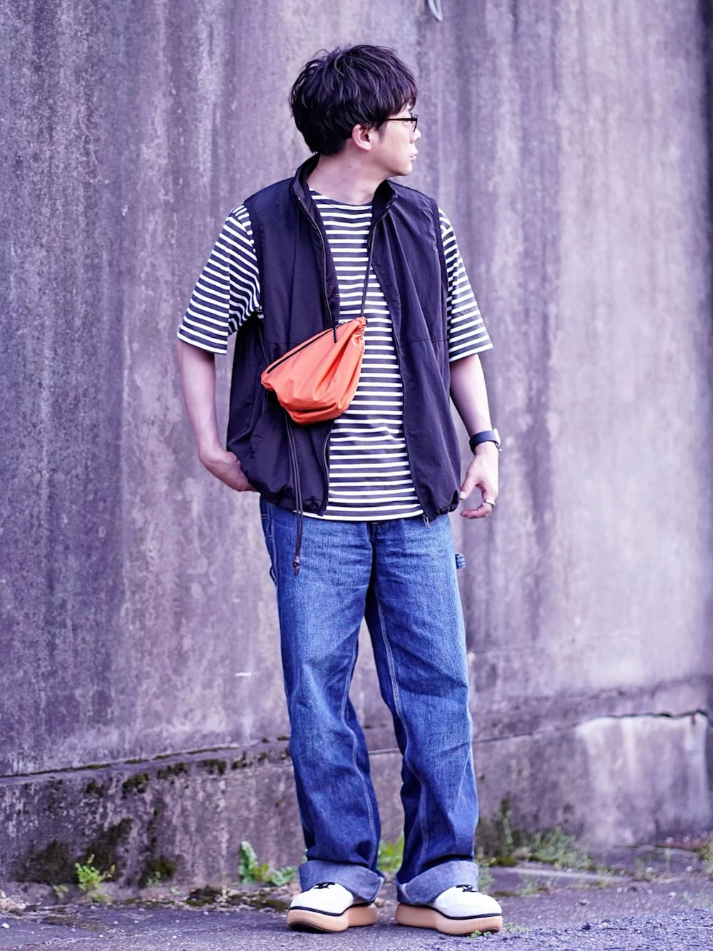 ブルー系のデニムパンツ、ブラック系のベスト、ブラック系のTシャツ/カットソーを着用したメンズの春コーディネートの1枚目の写真