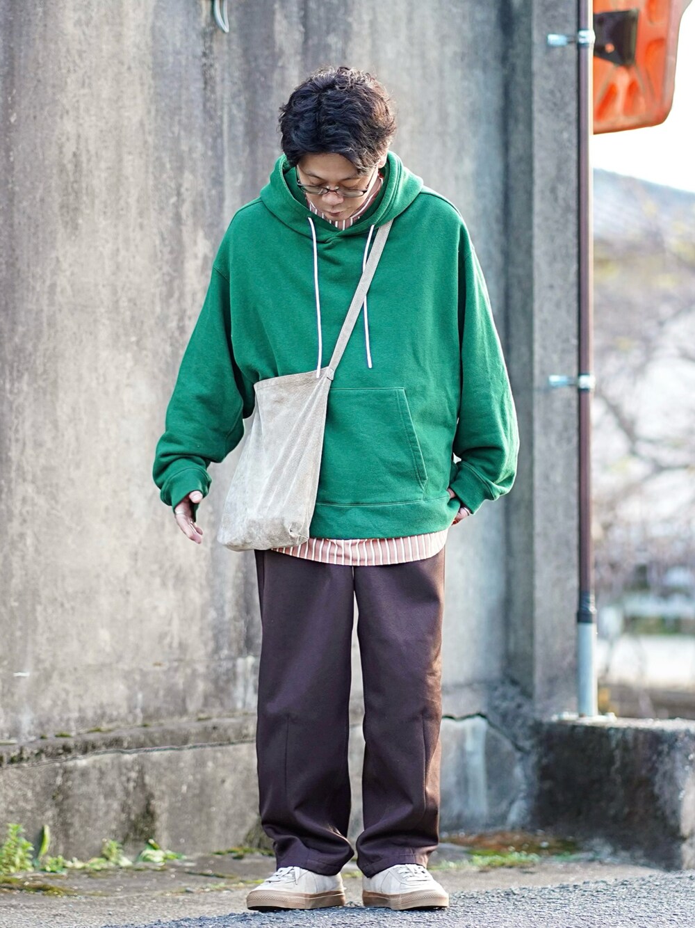 グリーン系のパーカー、オレンジ系のシャツ/ブラウス、ブラウン系のスラックスを着用したメンズの冬コーディネートの1枚目の写真