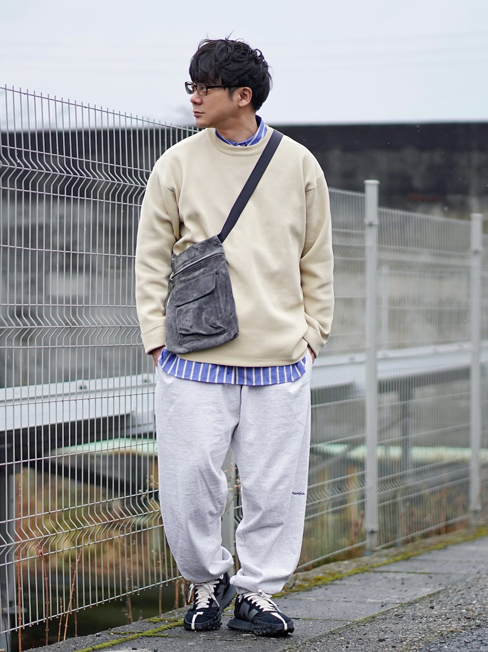 ベージュ系のニット/セーター、ブルー系のシャツ/ブラウス、グレー系のスウェットパンツを着用したメンズの春コーディネートの1枚目の写真