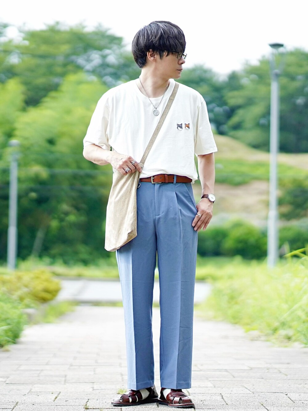 ホワイト系のTシャツ/カットソー、ブルー系のスラックス、ブラウン系のサンダルを着用したメンズの夏コーディネートの1枚目の写真