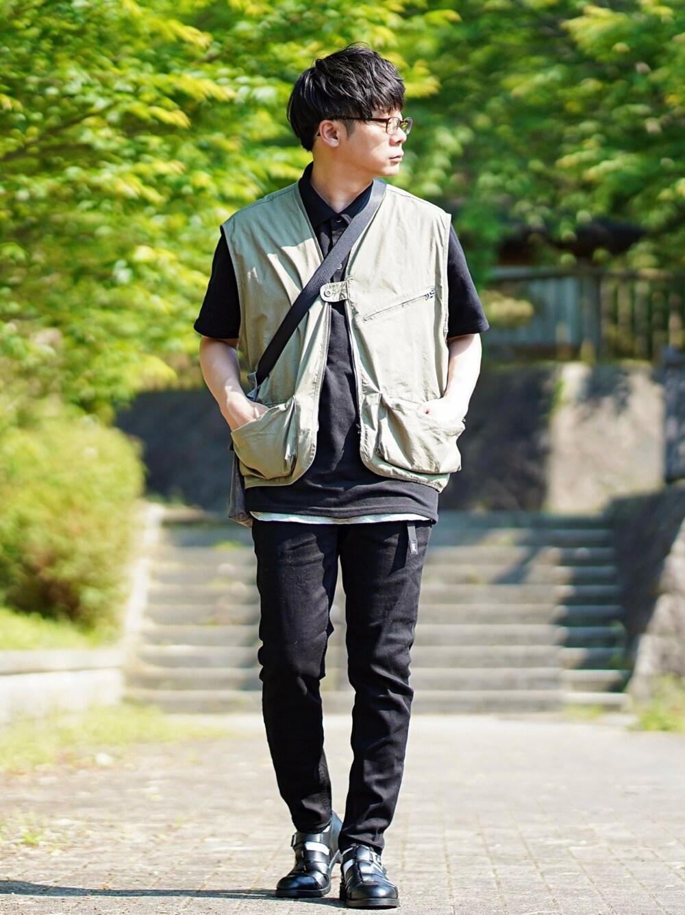 ブラック系のポロシャツ、グリーン系のベスト、グレー系のタンクトップを着用したメンズの春コーディネートの1枚目の写真