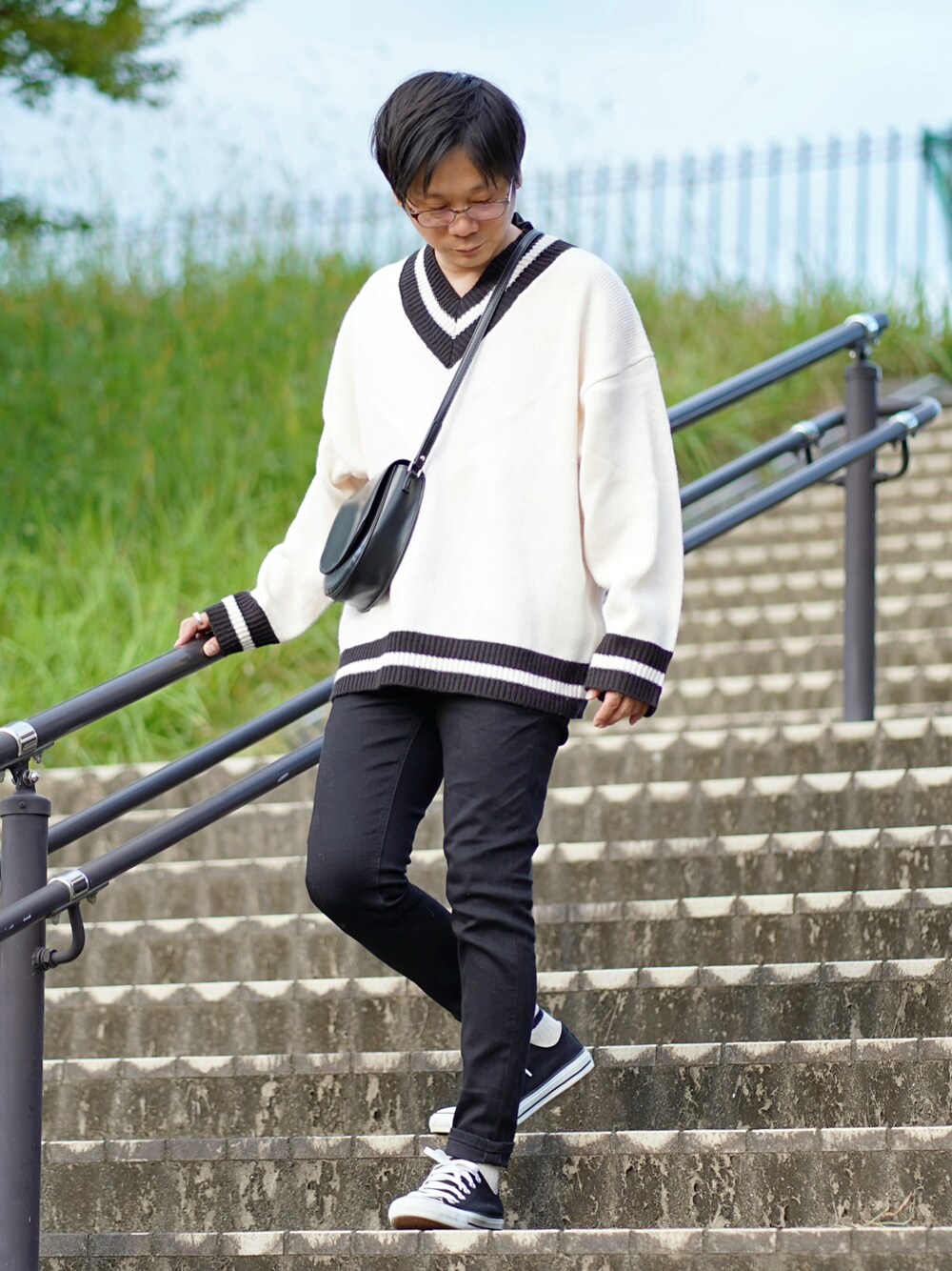 ホワイト系のニット/セーター、ブラック系のデニムパンツ、ブラック系のスニーカーを着用したメンズの秋コーディネートの1枚目の写真