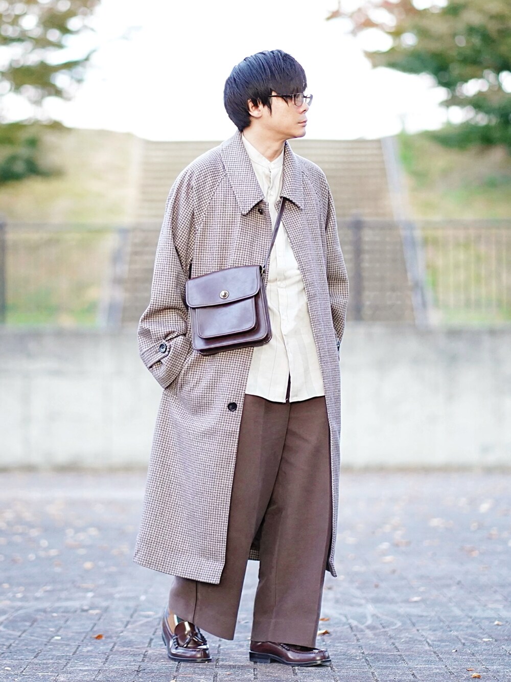 ブラウン系のステンカラーコート、ベージュ系のシャツ/ブラウス、ブラウン系のパンツを着用したメンズの秋コーディネートの1枚目の写真