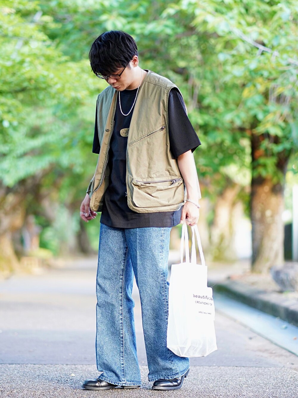 ブラック系のTシャツ/カットソー、グリーン系のベスト、ブルー系のデニムパンツを着用したメンズの夏コーディネートの1枚目の写真