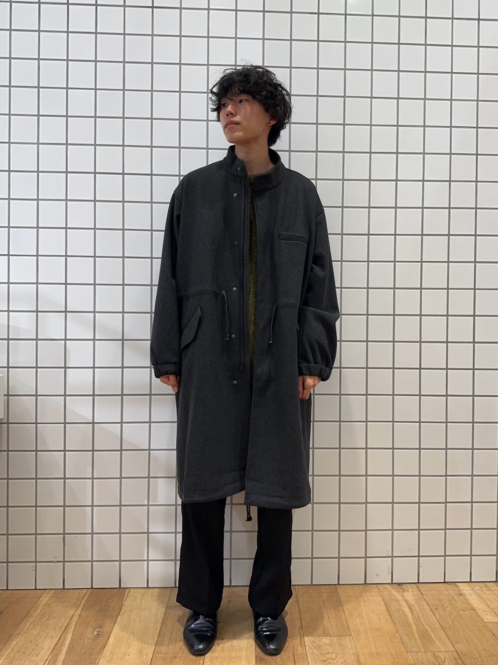 グレー系のモッズコート、グリーン系のニット/セーター、ブラック系のその他パンツを着用したメンズの秋コーディネートの1枚目の写真