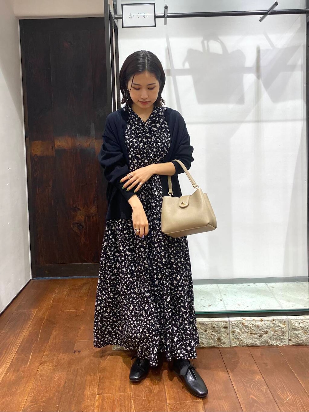 ブラック系のワンピース、ベージュ系のショルダーバッグ、ブラック系のカーディガン/ボレロを着用したレディースの夏コーディネートの1枚目の写真