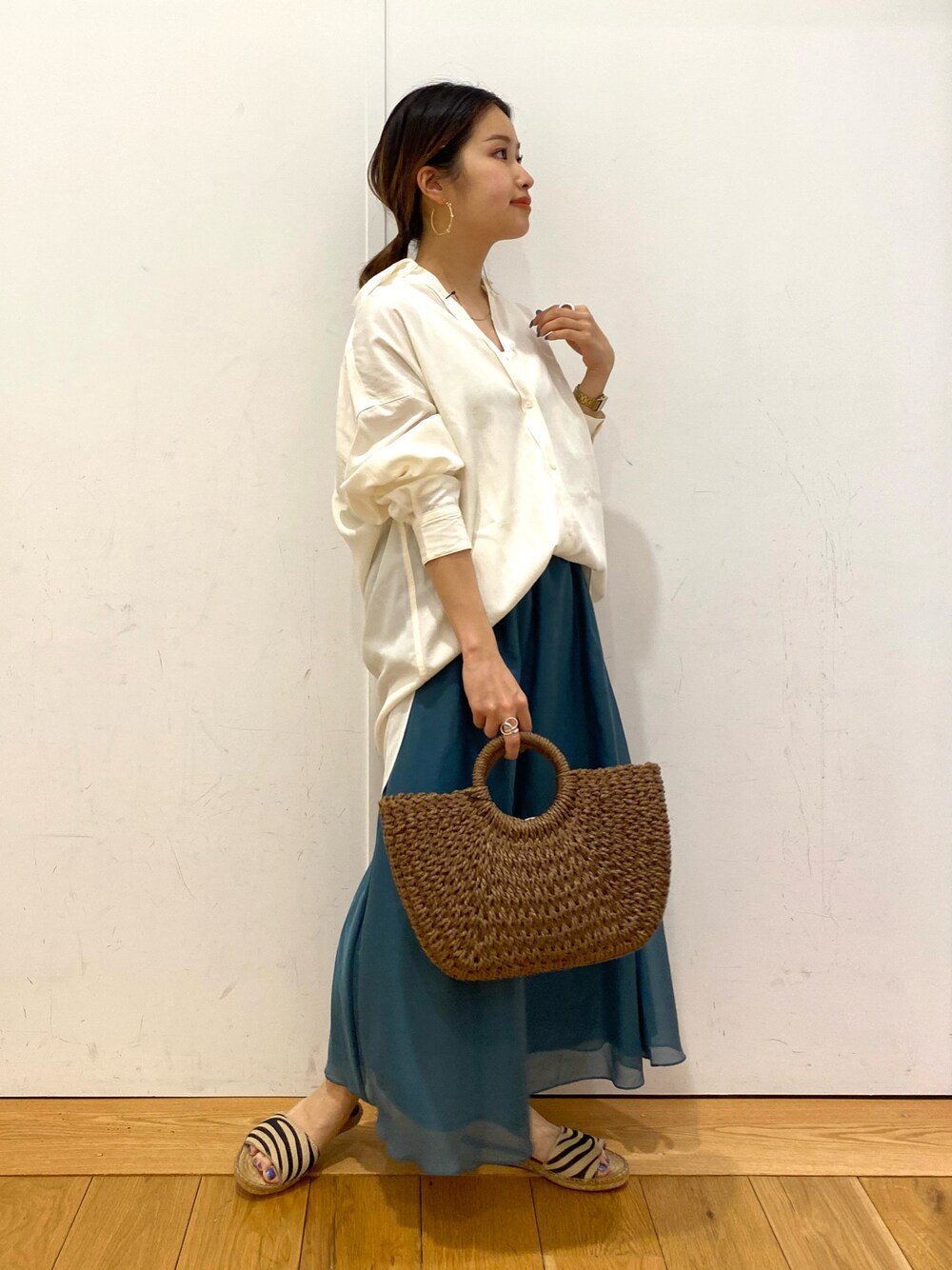 ブラウン系のハンドバッグ、ホワイト系のシャツ/ブラウス、ブルー系のスカートを着用したレディースの夏コーディネートの1枚目の写真