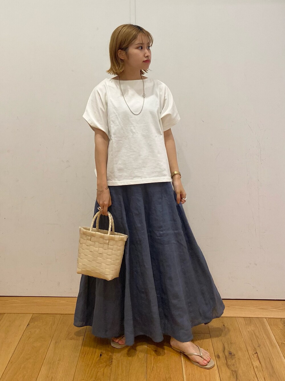 ホワイト系のTシャツ/カットソー、ブルー系のスカート、ベージュ系のトートバッグを着用したレディースの夏コーディネートの1枚目の写真