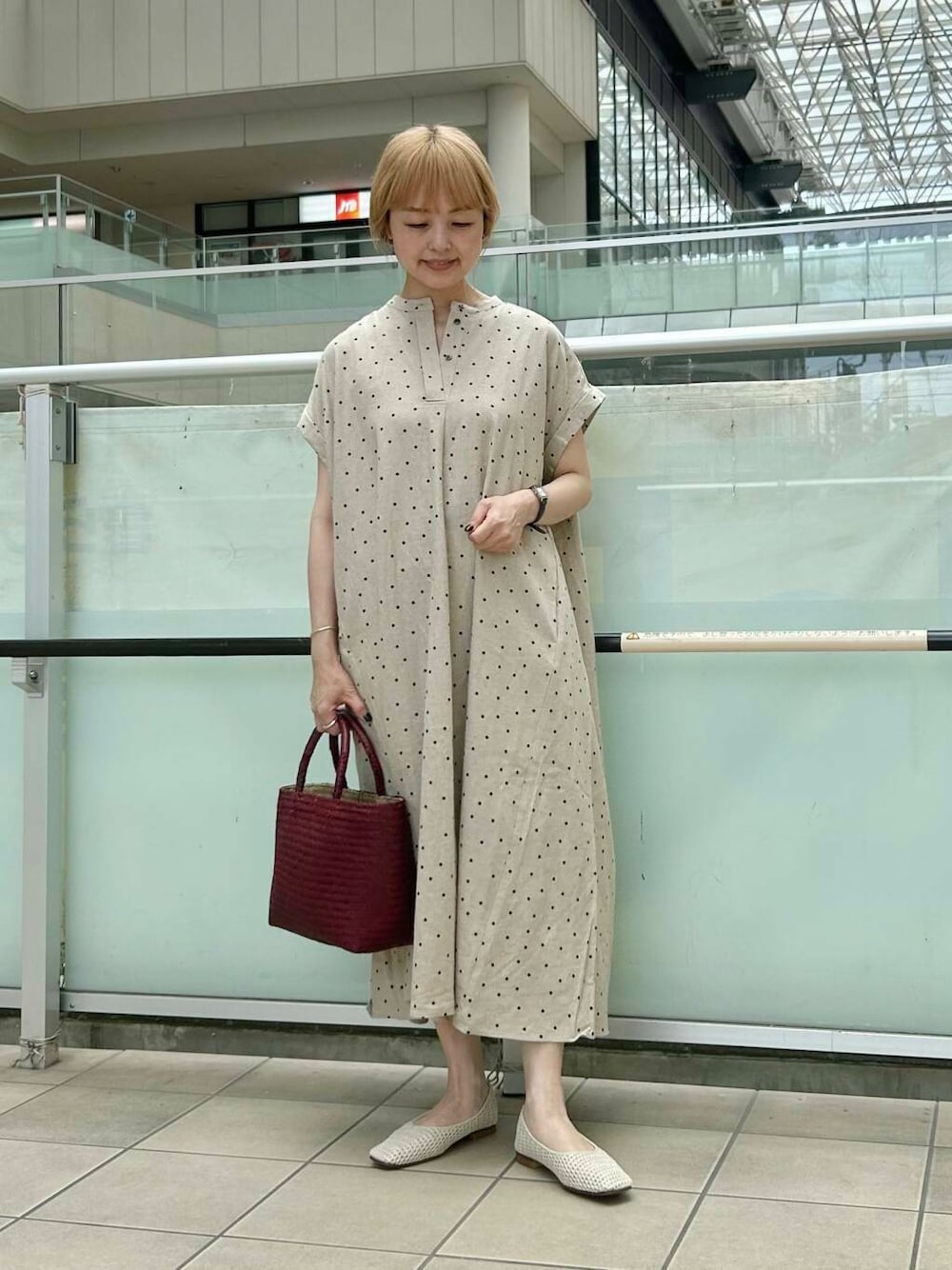 レッド系のトートバッグ、ホワイト系のバレエシューズ、ベージュ系のワンピースを着用したレディースの夏コーディネートの1枚目の写真