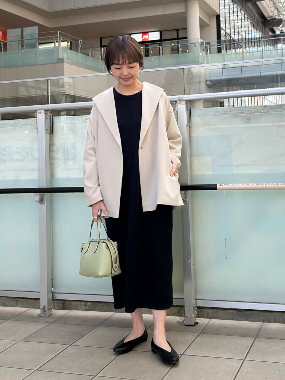 ブラック系のパンプス、ベージュ系のその他アウター、ブラック系のワンピースを着用したレディースの春コーディネートの1枚目の写真