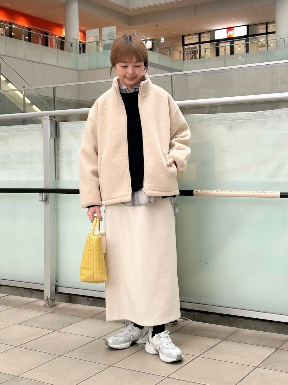 イエロー系のトートバッグ、グレー系のシャツ/ブラウス、シルバー系のスニーカーを着用したレディースの冬コーディネートの1枚目の写真