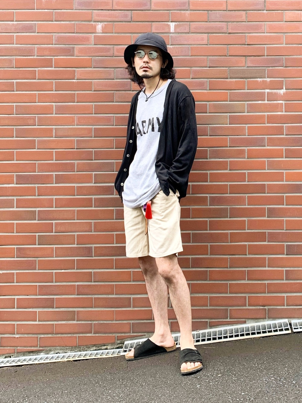 ブラック系のカーディガン/ボレロ、グレー系のTシャツ/カットソー、ベージュ系のチノパンツを着用したメンズの秋コーディネートの1枚目の写真