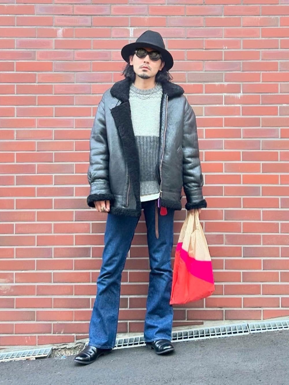 ブラック系のムートンコート、グレー系のニット/セーター、ホワイト系のTシャツ/カットソーを着用したメンズの冬コーディネートの1枚目の写真