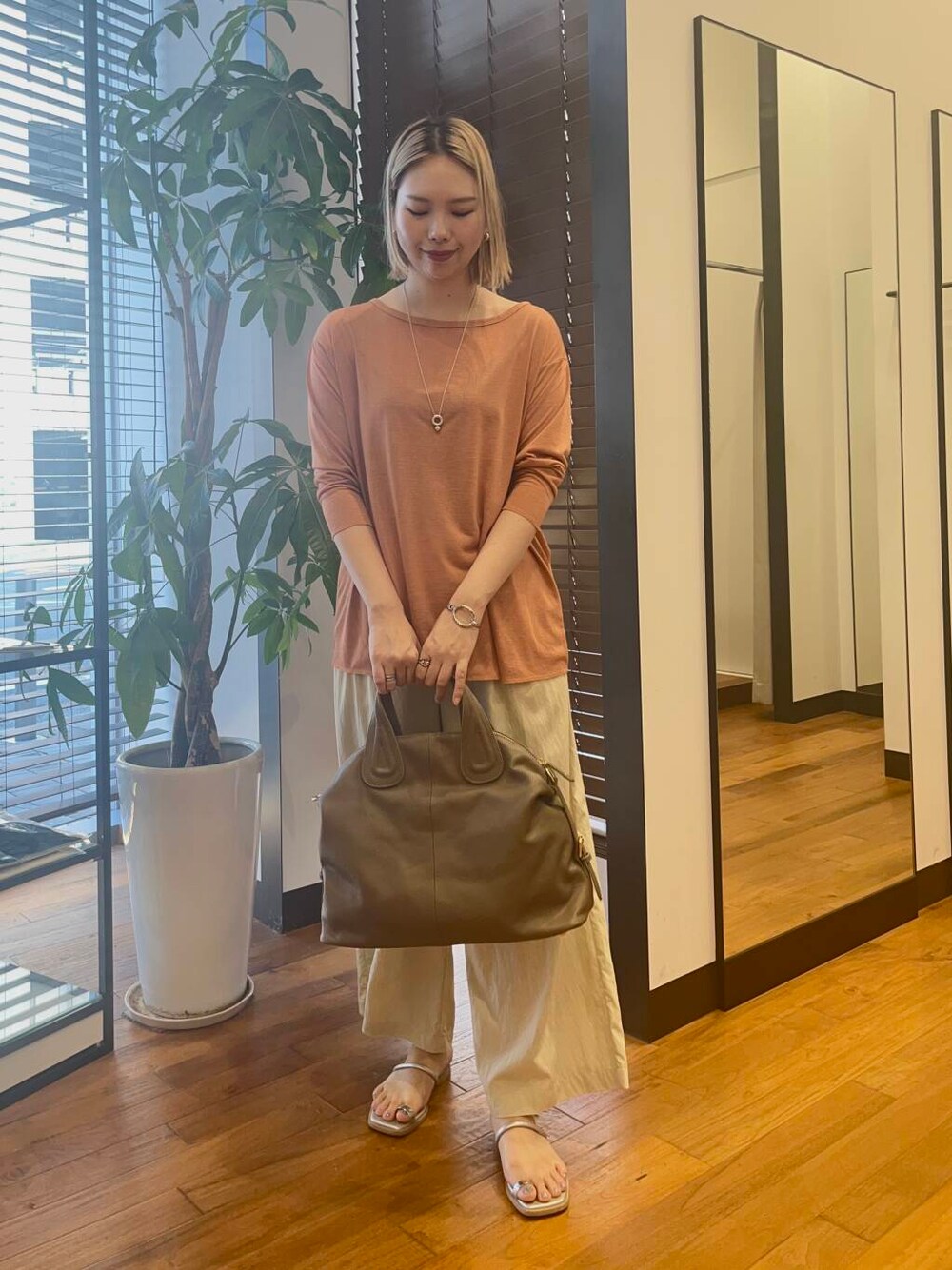 ベージュ系のその他パンツ、オレンジ系のTシャツ/カットソー、ベージュ系のボストンバッグを着用したレディースの夏コーディネートの1枚目の写真