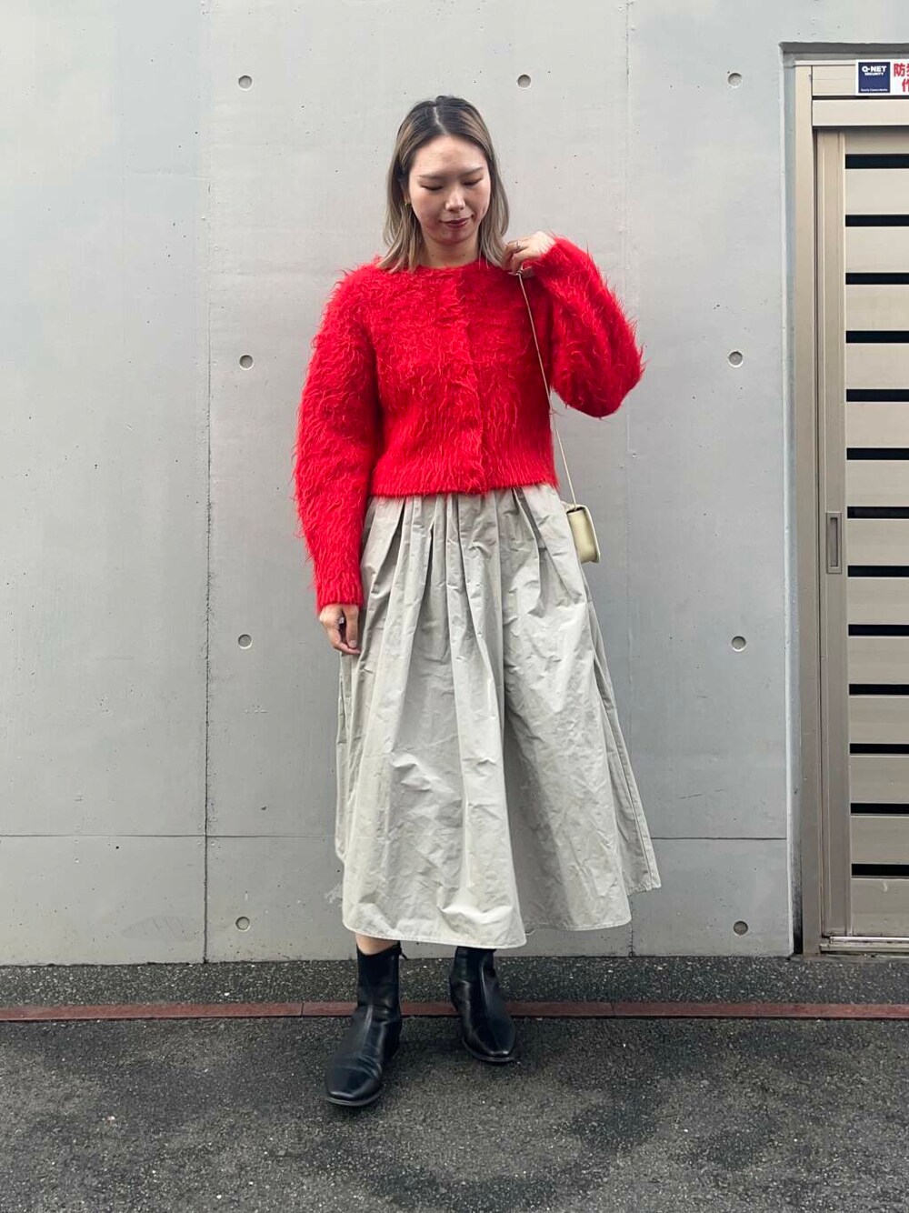 レッド系のカーディガン/ボレロ、ホワイト系のショルダーバッグ、グリーン系のスカートを着用したレディースの冬コーディネートの1枚目の写真