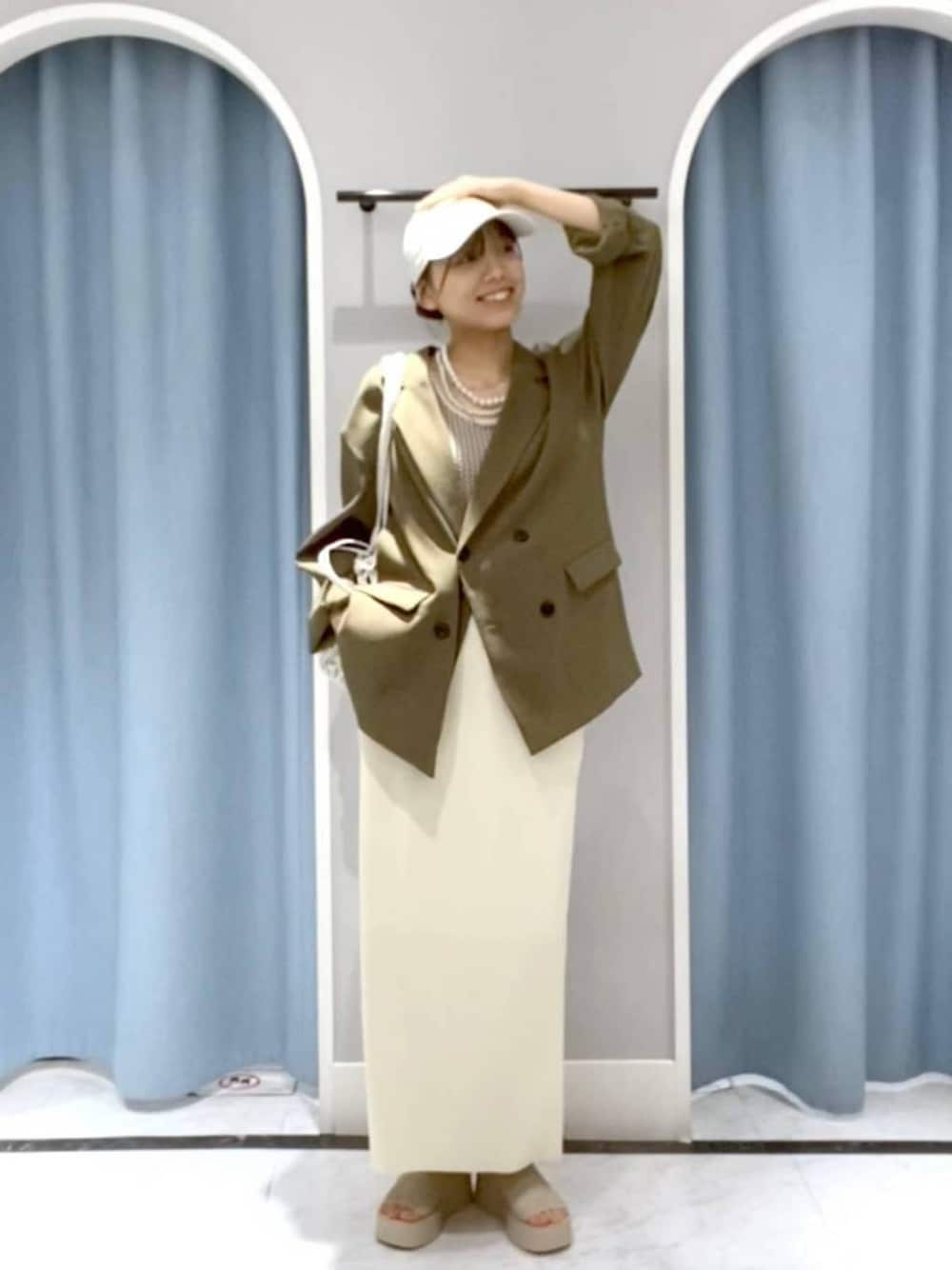 ホワイト系のスカート、グリーン系のテーラードジャケット、ホワイト系のサンダルを着用したレディースの春コーディネートの1枚目の写真