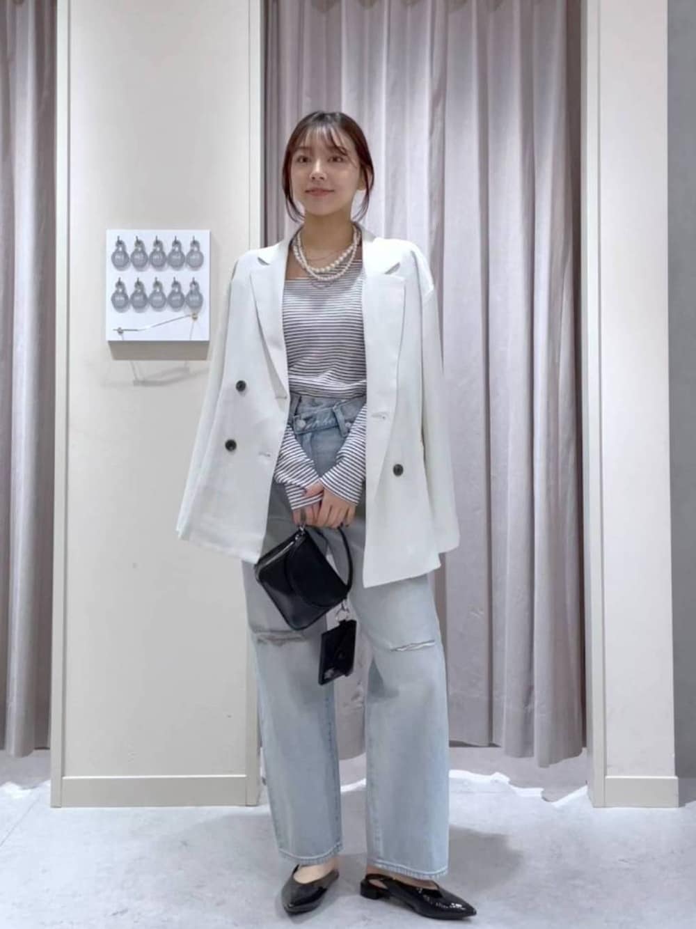 ホワイト系のテーラードジャケット、ブルー系のデニムパンツ、ブラック系のショルダーバッグを着用したレディースの春コーディネートの1枚目の写真