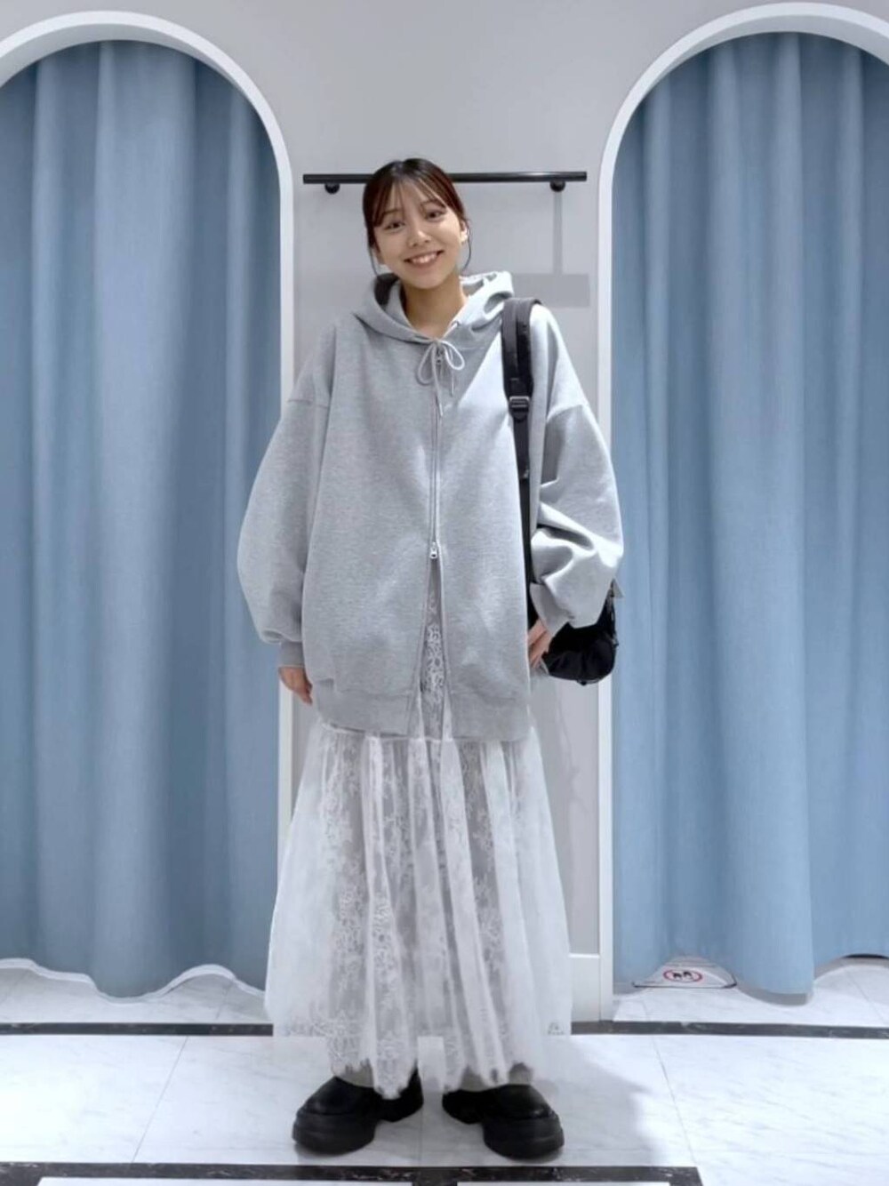 グレー系のデニムパンツ、ブラック系のバックパック/リュック、ホワイト系のスカートを着用したレディースの春コーディネートの1枚目の写真