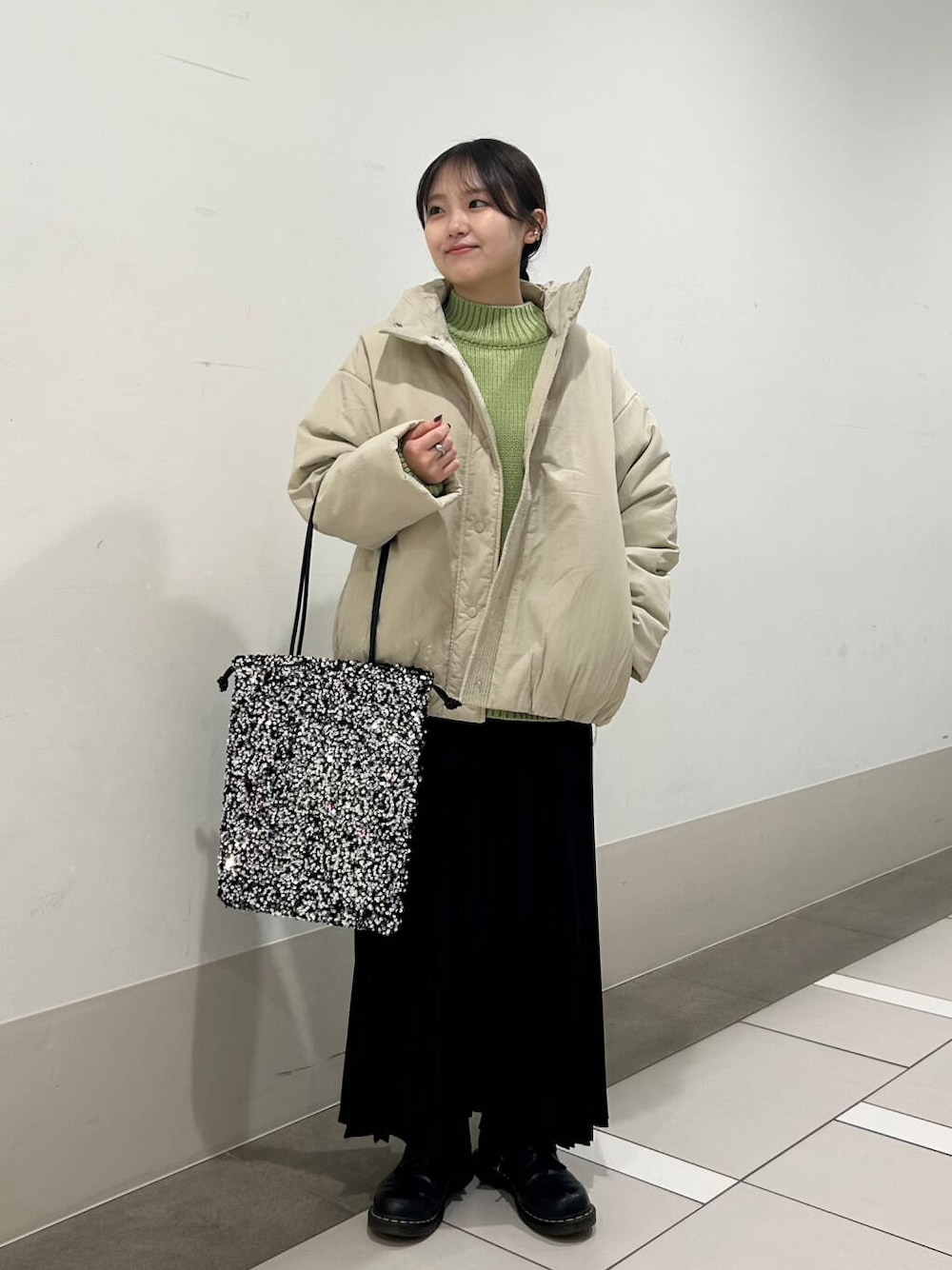 ベージュ系のブルゾン、シルバー系のトートバッグ、ブラック系のスカートを着用したレディースの冬コーディネートの1枚目の写真