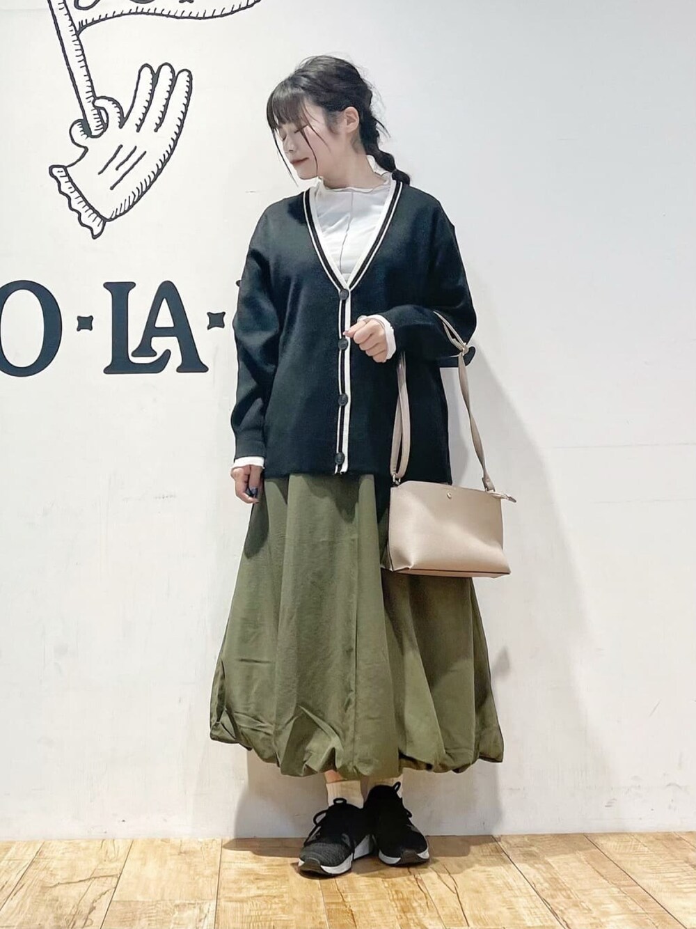 ブラック系のカーディガン/ボレロ、グリーン系のスカート、ホワイト系のTシャツ/カットソーを着用したレディースの冬コーディネートの1枚目の写真
