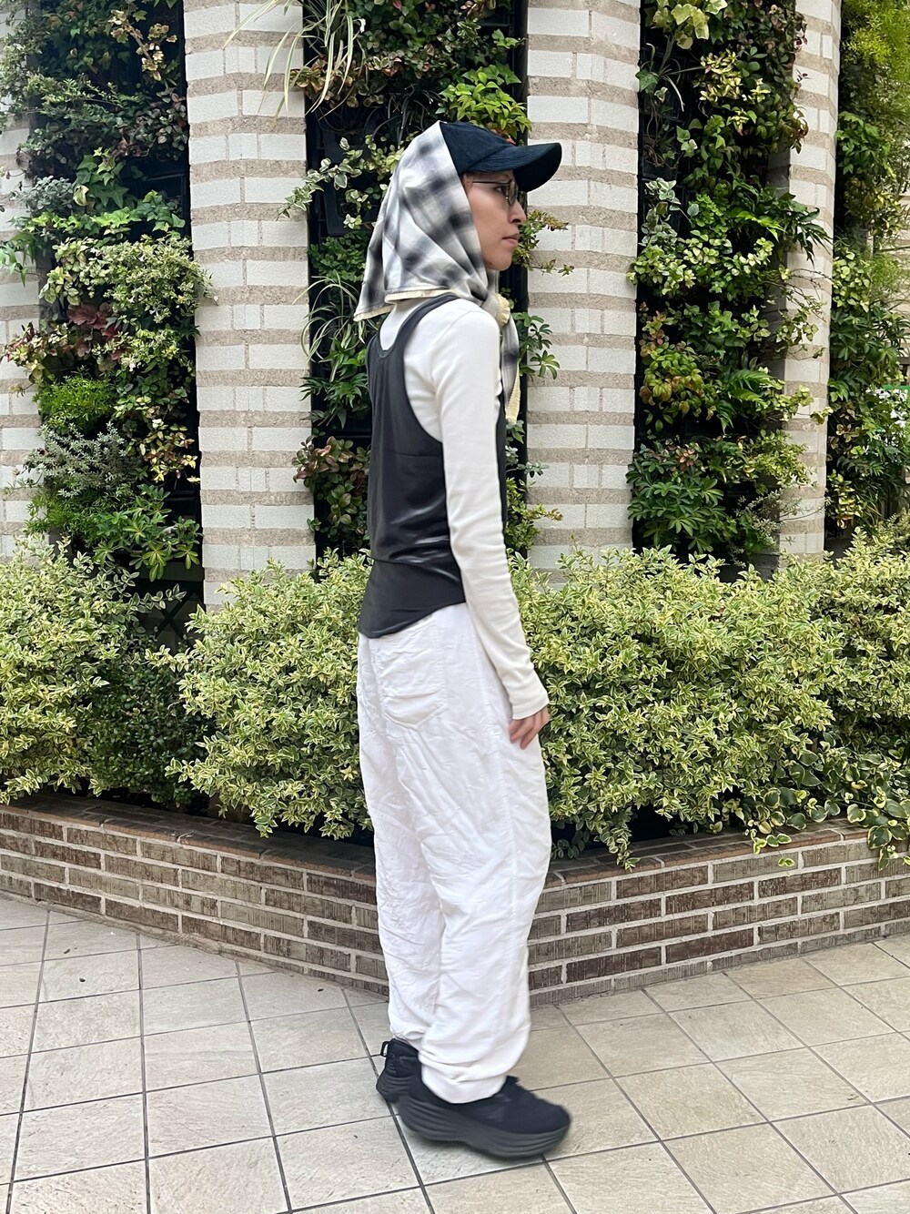 グレー系のタンクトップ、ブラック系のスニーカー、ブルー系のキャップを着用したレディースの秋コーディネートの1枚目の写真