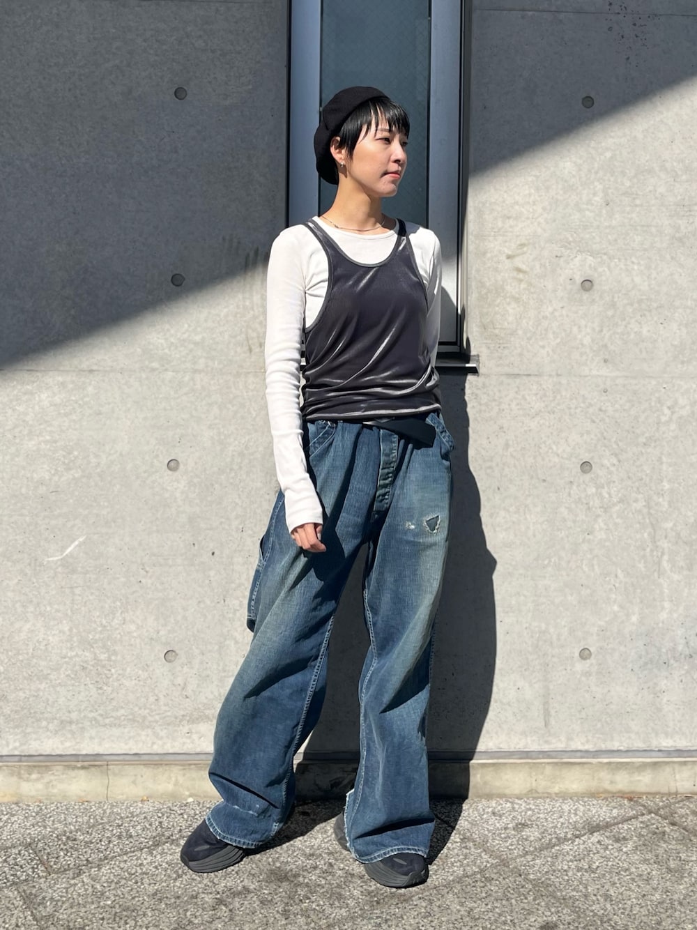 グレー系のタンクトップ、ブルー系のデニムパンツ、ブラック系のスニーカーを着用したレディースの冬コーディネートの1枚目の写真