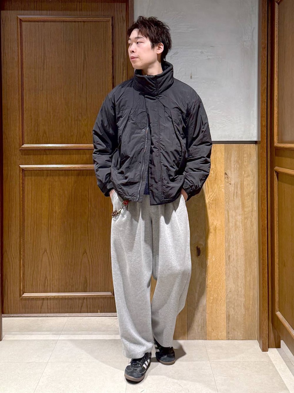 ブラック系のダウンジャケット/コート、ブルー系のニット/セーター、グレー系のスウェットパンツを着用したメンズの冬コーディネートの1枚目の写真