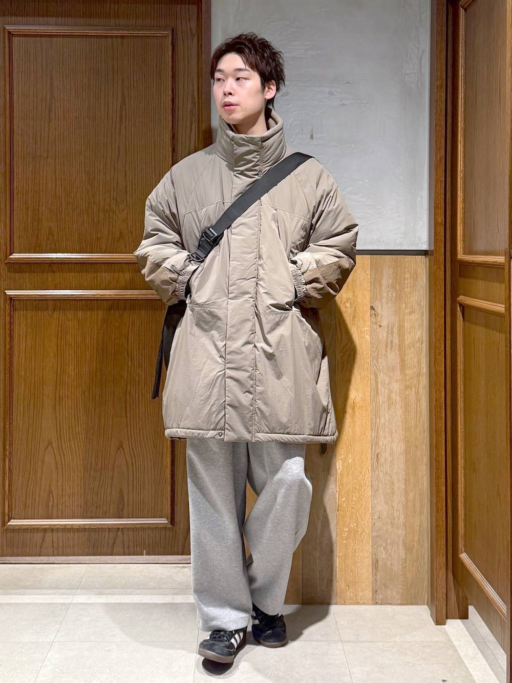 グリーン系のダウンジャケット/コート、ブラック系のポロシャツ、グレー系のスウェットパンツを着用したメンズの秋コーディネートの1枚目の写真