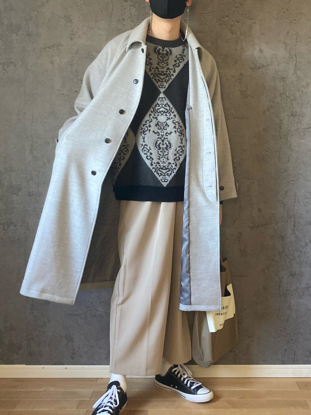 グレー系のニット/セーター、グレー系のその他アウター、ブラウン系のスラックスを着用したメンズの冬コーディネートの1枚目の写真