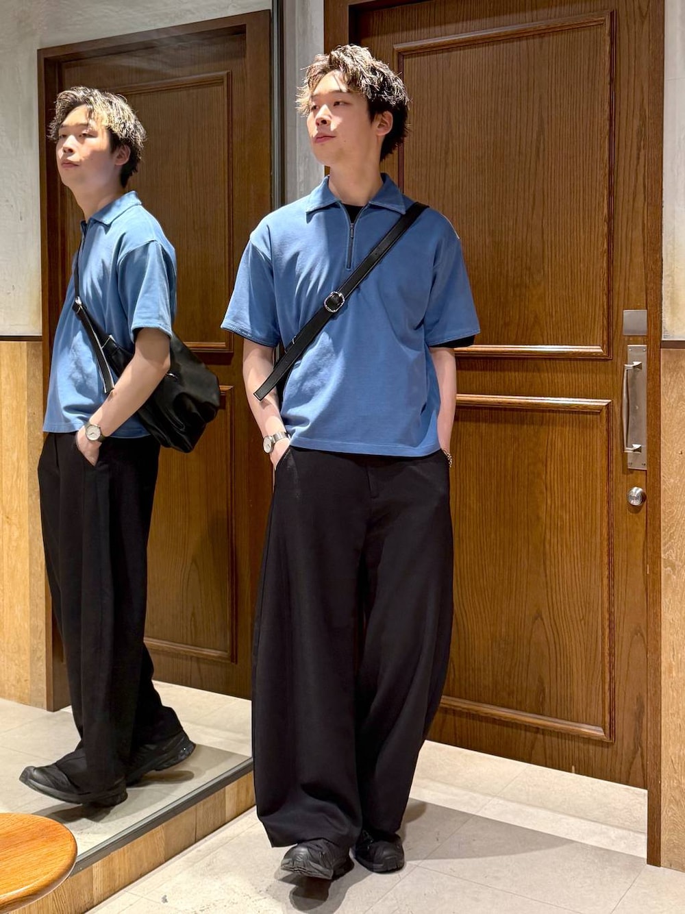 ブラック系のスラックス、ブラック系のショルダーバッグ、ブルー系のTシャツ/カットソーを着用したメンズの春コーディネートの1枚目の写真