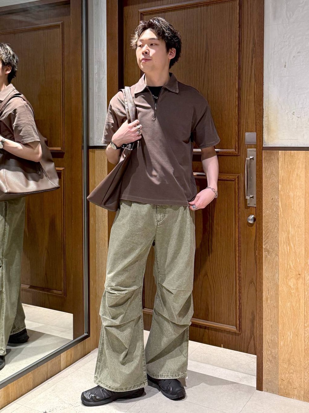 ブラウン系のトートバッグ、グリーン系のカーゴパンツ、ブラウン系のTシャツ/カットソーを着用したメンズの春コーディネートの1枚目の写真