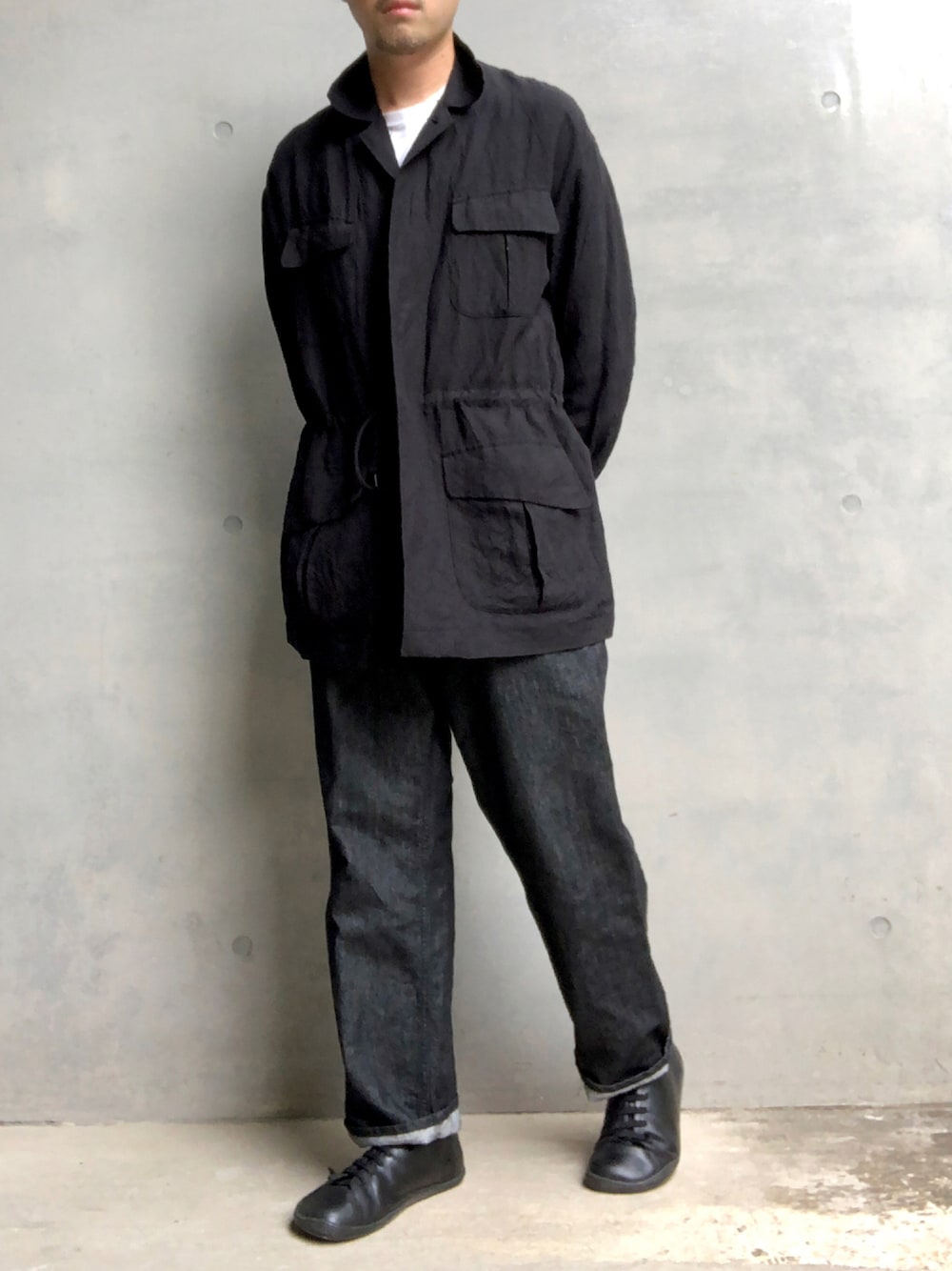 ブラック系のデニムパンツ、ブラック系のミリタリージャケット、ブラック系のスニーカーを着用したメンズの秋コーディネートの1枚目の写真