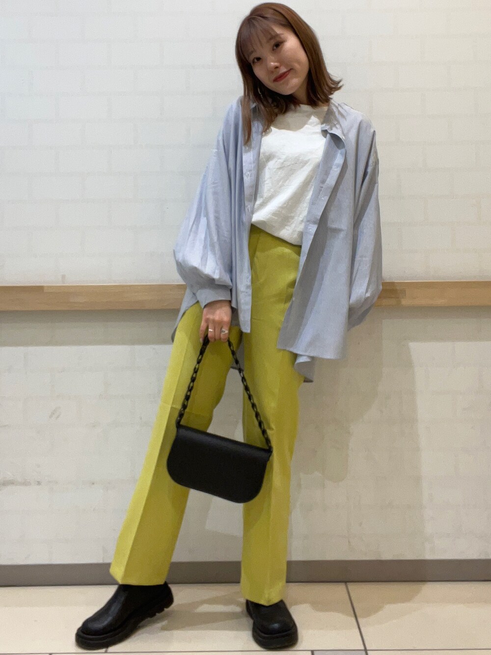 イエロー系のその他パンツ、ブルー系のシャツ/ブラウス、ブラック系のハンドバッグを着用したレディースの冬コーディネートの1枚目の写真