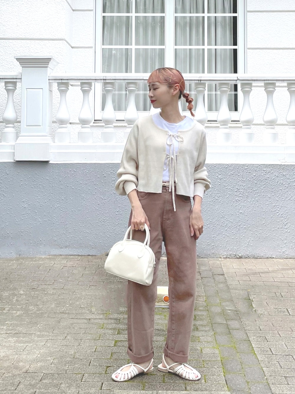 ブラウン系のデニムパンツ、ベージュ系のボストンバッグ、ホワイト系のサンダルを着用したレディースの秋コーディネートの1枚目の写真
