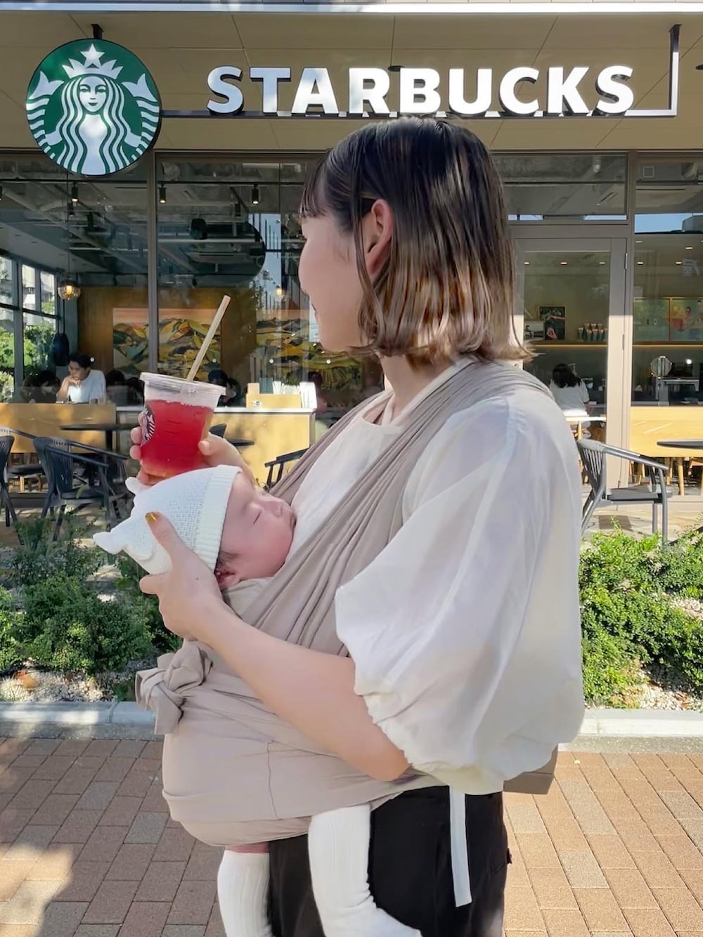 ホワイト系のシャツ/ブラウス、ベージュ系の抱っこ紐/ベルトカバー/スリング、ホワイト系のその他ベビーウェアを着用したレディースの秋コーディネートの1枚目の写真