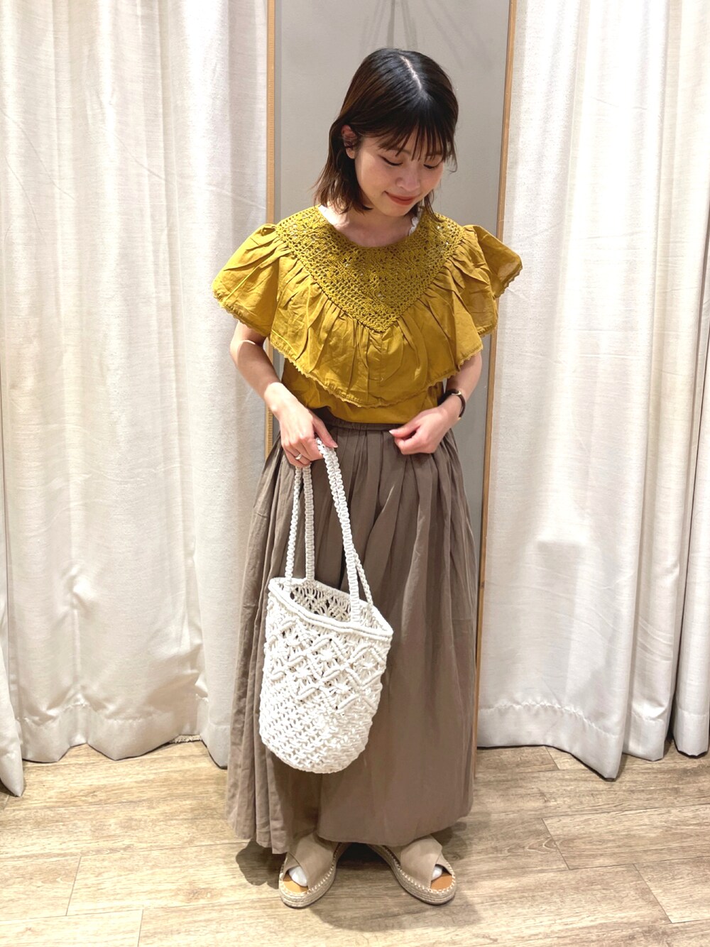 ホワイト系のトートバッグ、イエロー系のシャツ/ブラウス、ブラウン系のスカートを着用したレディースの春コーディネートの1枚目の写真
