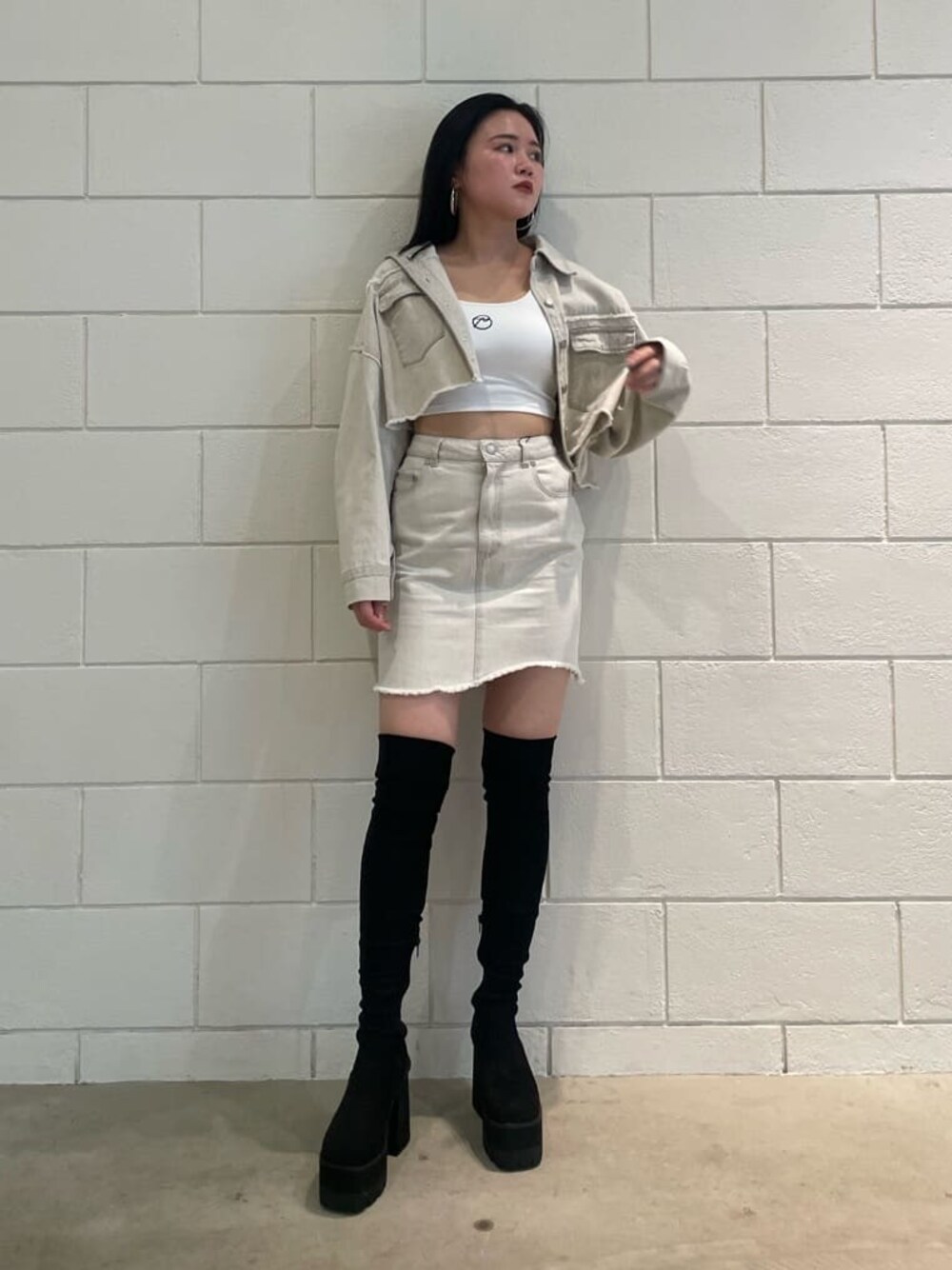 ホワイト系のデニムジャケット、ホワイト系のタンクトップ、ブラック系のブーツを着用したレディースの夏コーディネートの1枚目の写真