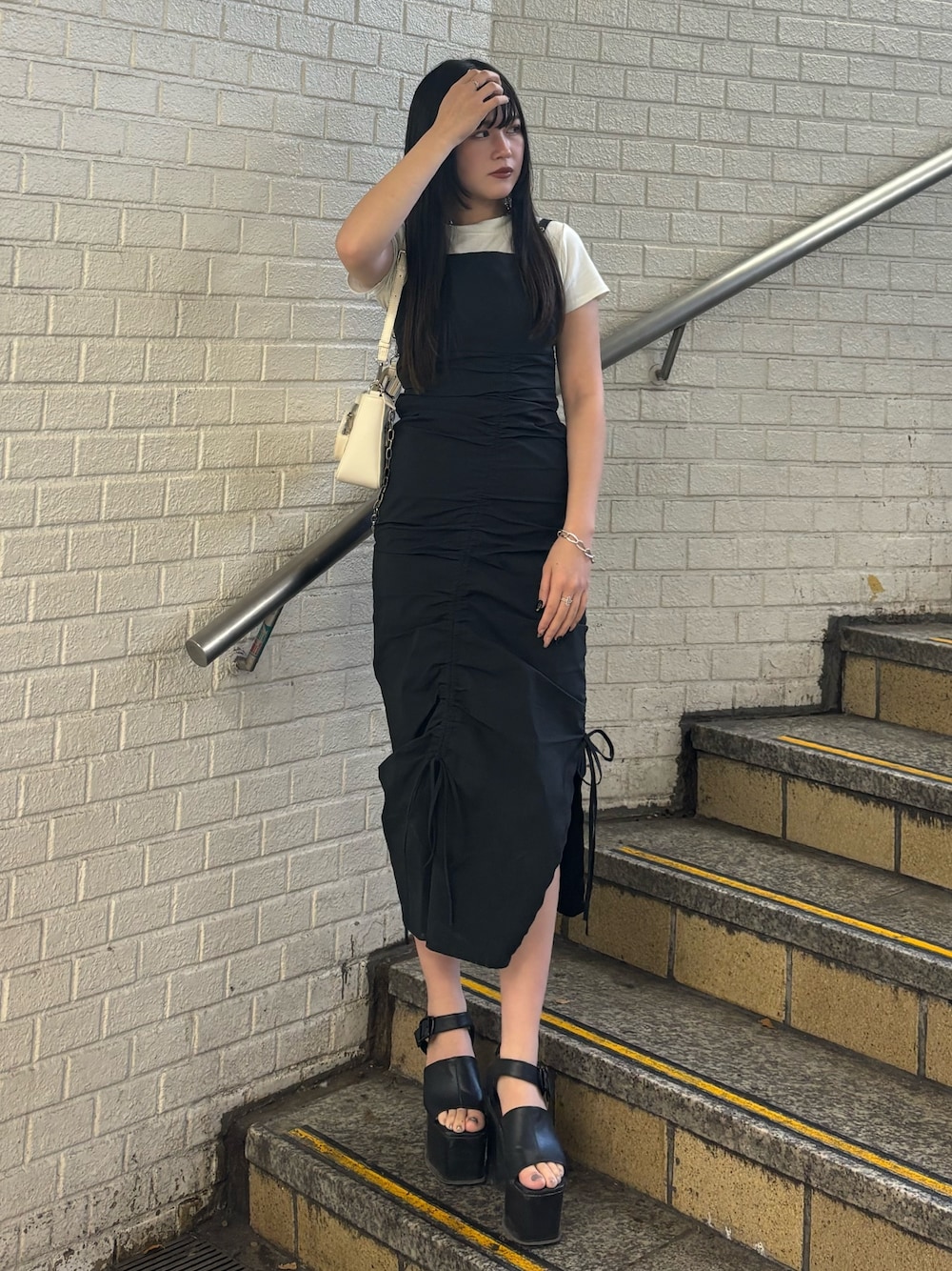 ブラック系のサンダル、ホワイト系のショルダーバッグ、ホワイト系のTシャツ/カットソーを着用したレディースの春コーディネートの1枚目の写真