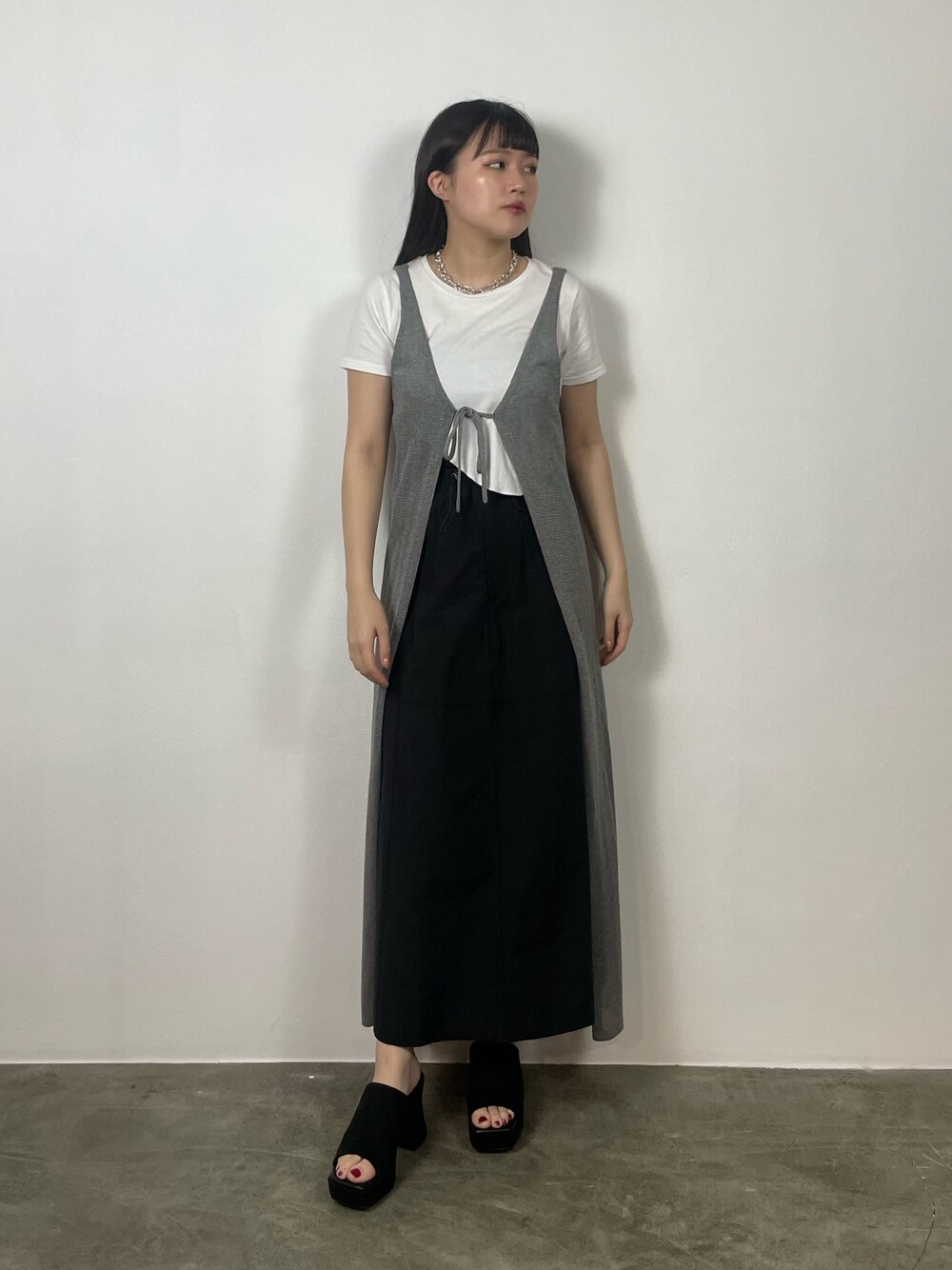 ブラック系のスカート、ホワイト系のTシャツ/カットソー、ブラック系のサンダルを着用したレディースの夏コーディネートの1枚目の写真