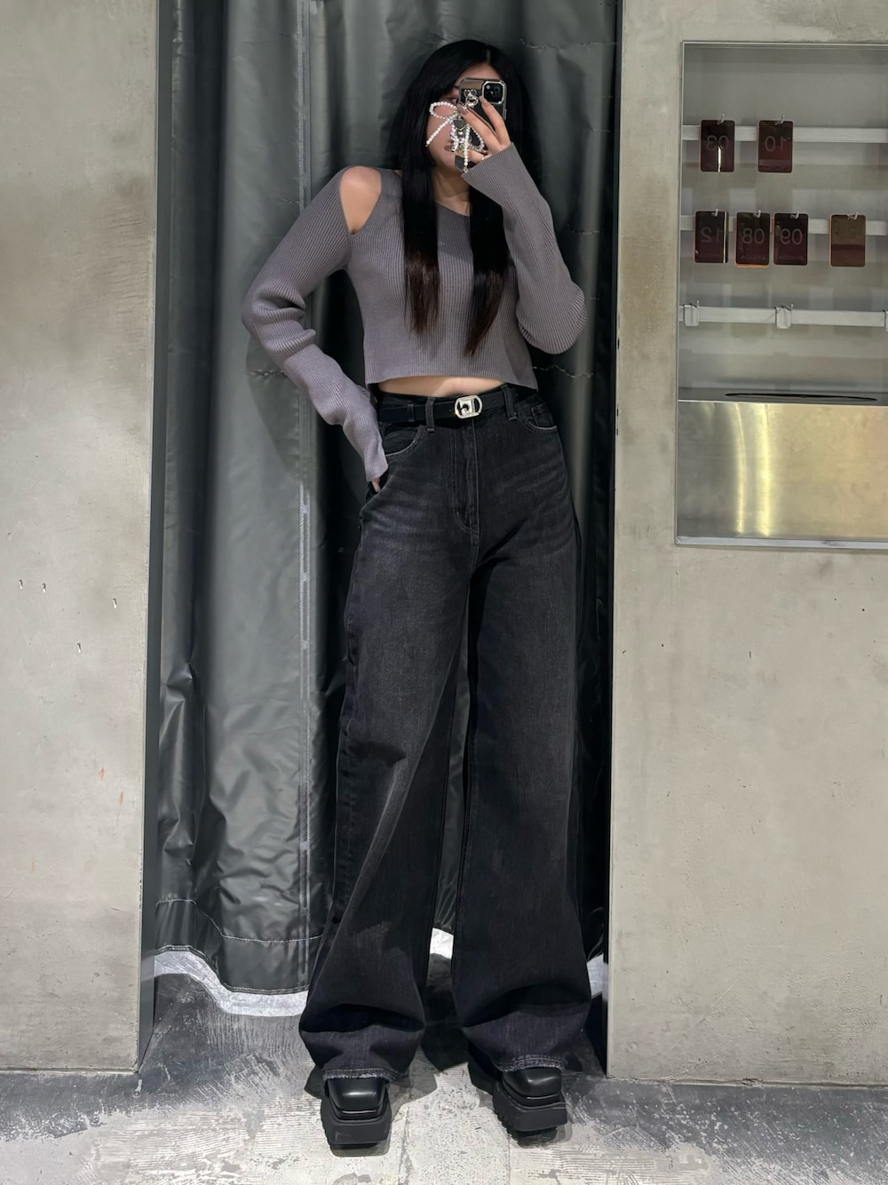 ブルー系のデニムパンツ、グレー系のニット/セーター、ブラック系のブーツを着用したレディースの秋コーディネートの1枚目の写真