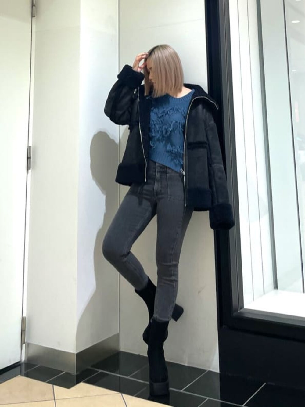 ブラック系のブーツ、グレー系のデニムパンツ、ブラック系のムートンコートを着用したレディースの冬コーディネートの1枚目の写真